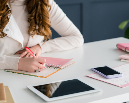 a woman is writing on a notebook